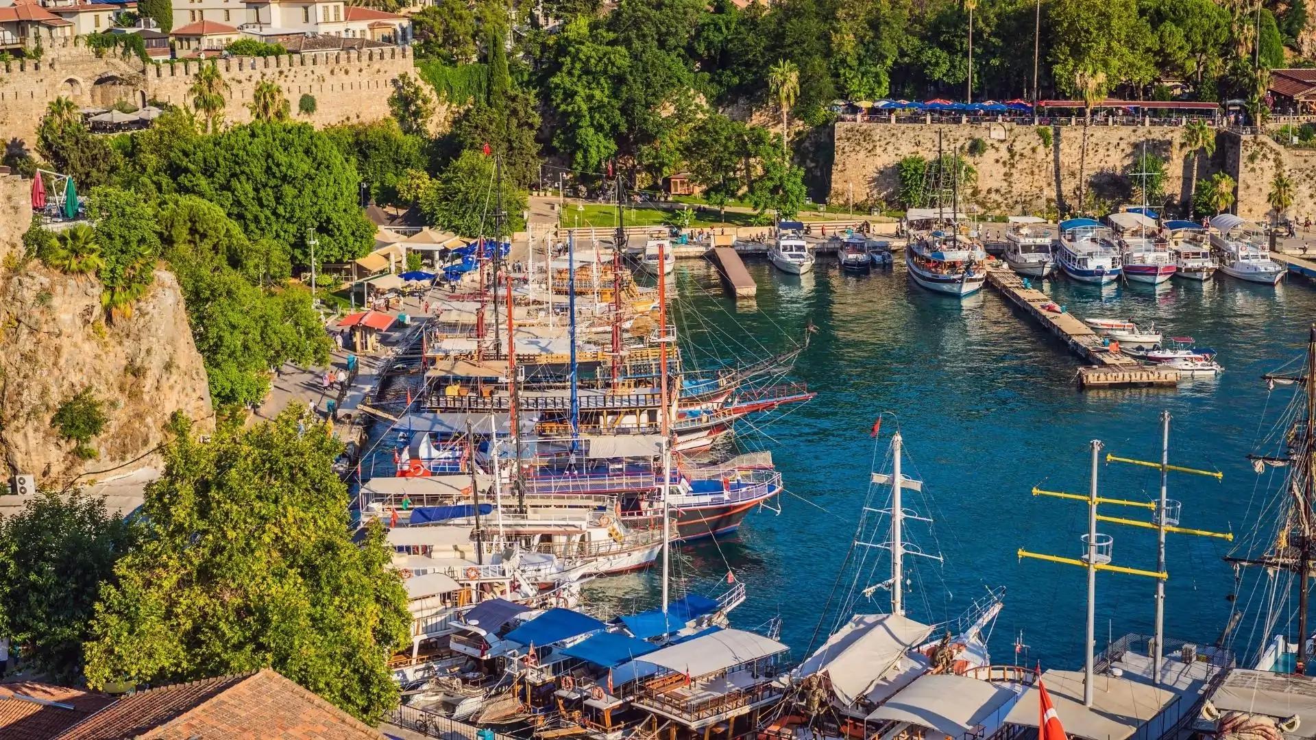 Panoramic view of Antalya Old Harbor with traditional boats, ancient city walls, and Mediterranean scenery.