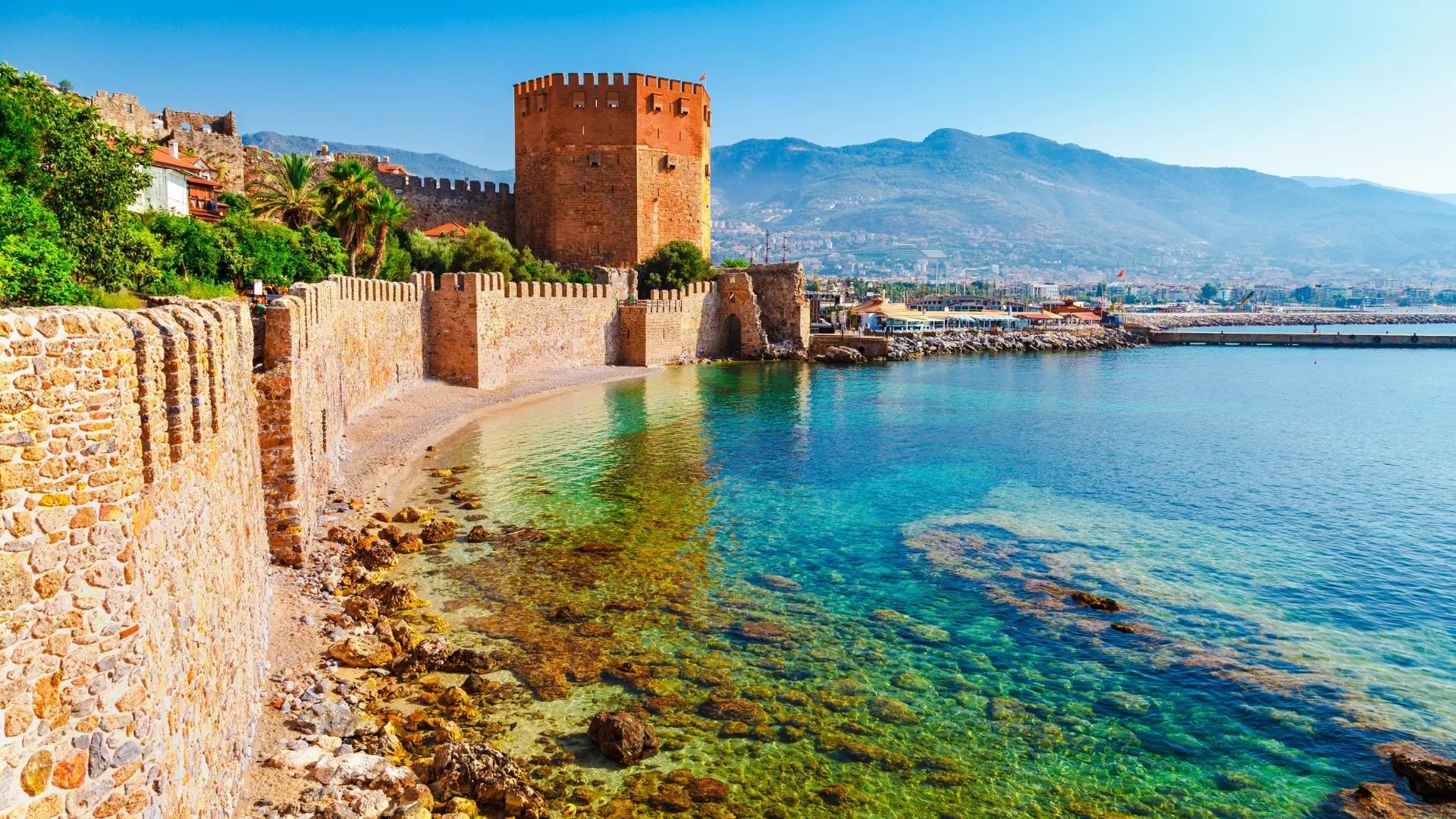 Alanya Red Tower and historic castle walls overlooking the turquoise Mediterranean coast of the Turkish Riviera.
